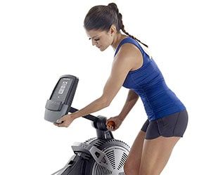 Woman adjusting monitor dispaly of Nordic Track RX800 rowing machine